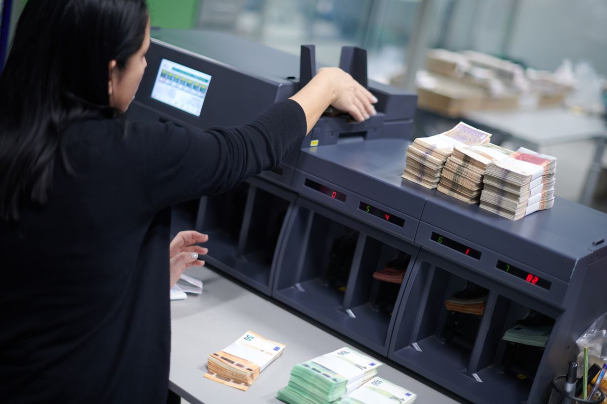 Operadora cargando billetes en una clasificadora de alto volumen